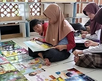 Anak-anak duduk dan berbaring di lantai, membaca buku cerita bersama, dengan buku-buku tergelar di depan mereka.